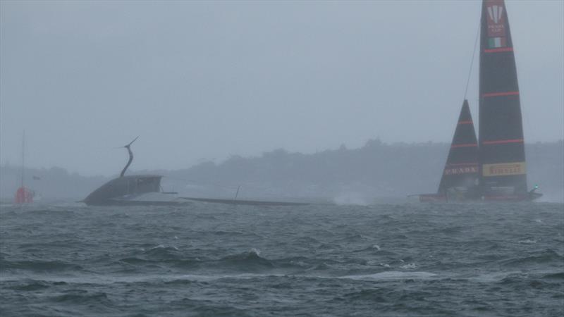 Luna Rossa sails past American Magic, in the rain squall, as Patriot's mast hits the water after capsizing at 47kts - Hauraki Gulf - January 17, 2021 - Prada Cup - 36th America's Cup - photo © Richard Gladwell - Sail-World.com / nz